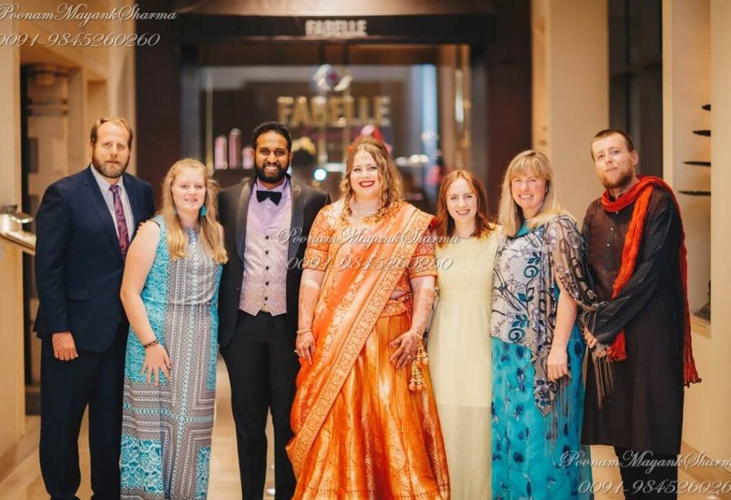 A festive Indo-Western wedding planned by Poonam Mayank Sharma in Bangalore, India. The bride in orange saree and the groom in tuxedo along with their friends and family showcases a beautiful blend of cultures.